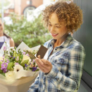 modern-woman-standing-at-her-door-accepting-a-delivery-of-flowers
