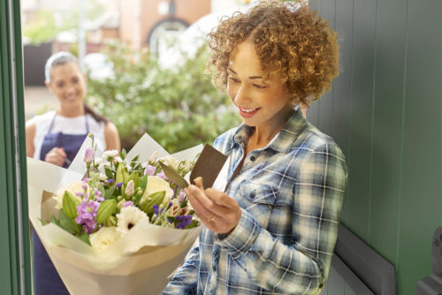 modern-woman-standing-at-her-door-accepting-a-delivery-of-flowers