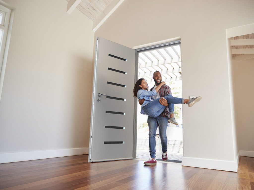 man-carrying-woman-into-new-home-through-stylish-door