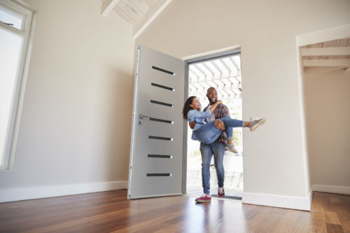 man-carrying-woman-into-new-home-through-stylish-door